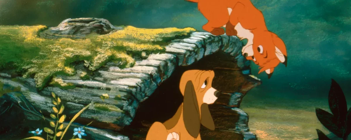 Un jeune renard se tient au sommet d'un rocher, regardant d'un air ludique un jeune chien assis en contrebas dans un décor forestier coloré du film de Disney "Rox et Rouky.