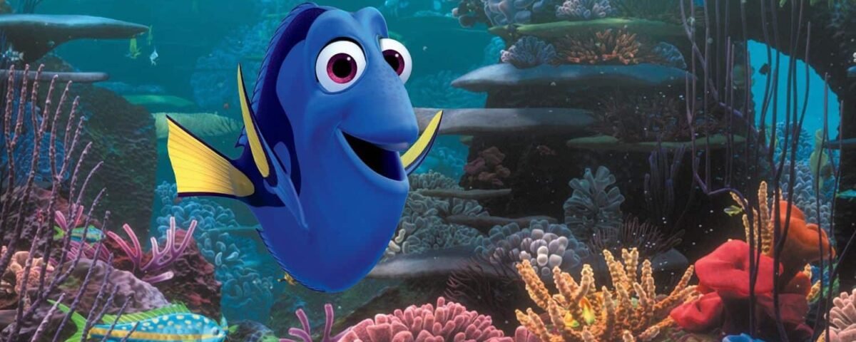 Image animée de Dory, un poisson bleu et jaune du « Monde de Nemo », nageant joyeusement près d'un récif de corail vibrant avec diverses plantes sous-marines colorées et une vie marine.
