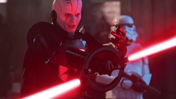 Un personnage à la peau pâle et aux marques faciales tenant un volant, vêtu d'un équipement tactique sombre, avec un faisceau de kenobi rouge traversant la scène et une silhouette floue dans un casque blanc dans le