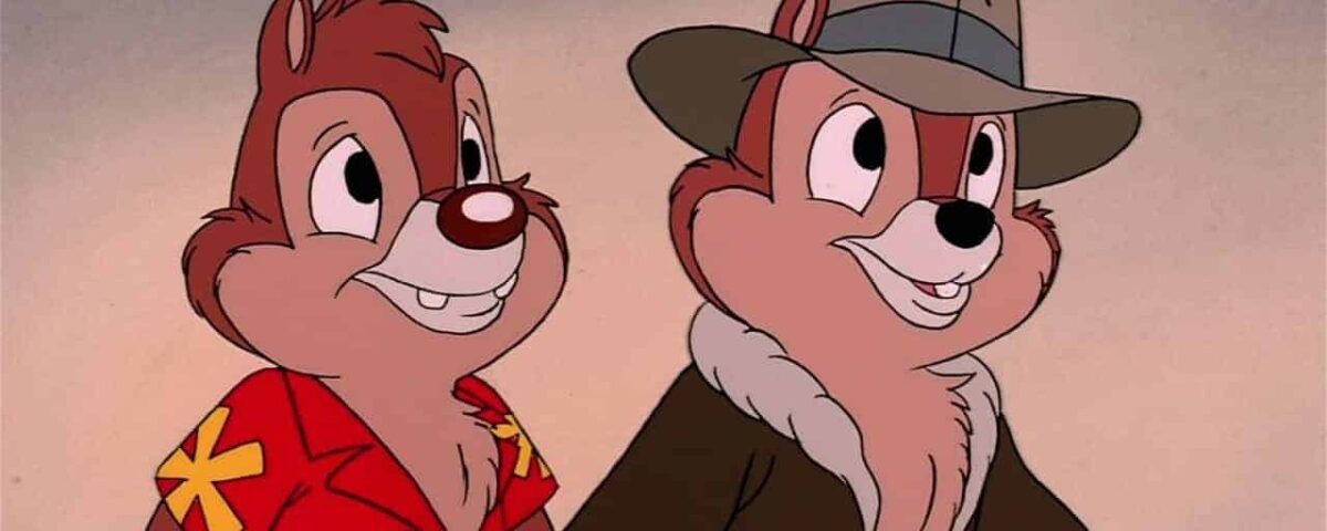 Deux tamias animés, l'un vêtu d'une chemise rouge à fleurs jaunes et l'autre portant une veste marron et un chapeau vert, souriant et debout côte à côte, sont connus sous le nom de Disney's Tic.