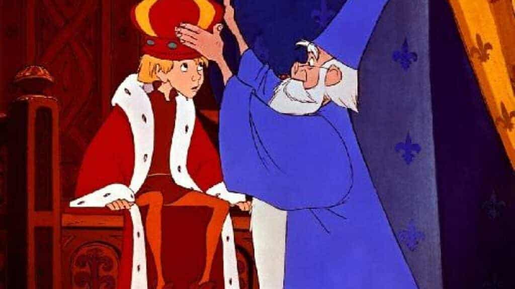 Une scène animée mettant en scène un jeune prince en robe rouge et blanche assis sur un trône et Merlin l'Enchanteur en robe bleue plaçant une couronne sur la tête du prince à l'intérieur d'un grand