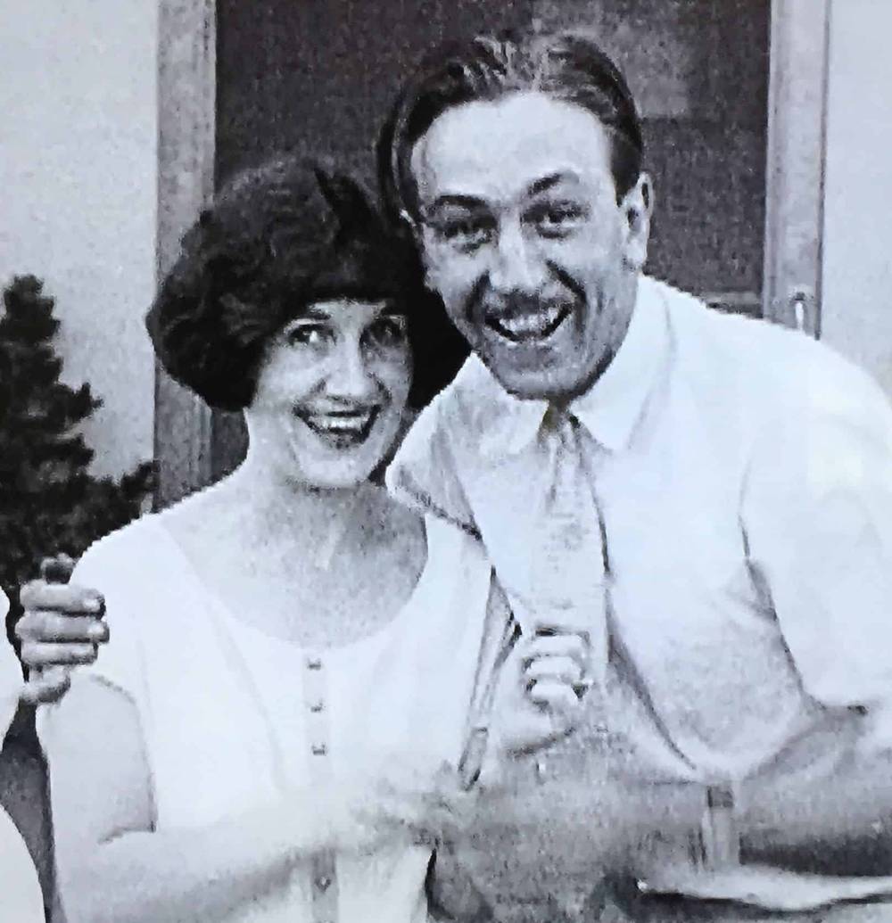 Photo en noir et blanc d'un homme et d'une femme souriants posant ensemble au studio d'animation Walt Disney, l'homme avec un bras autour de la femme, tous deux vêtus de vêtements vintage.
