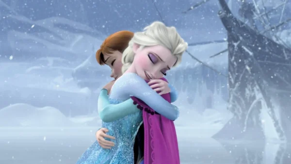 Elsa et Anna de « La Reine des Neiges » s'embrassent dans un paysage enneigé, exprimant un moment d'amour fraternel et de véritable réconciliation.