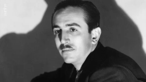 Portrait en noir et blanc d'un homme avec une moustache soignée, vêtu d'un costume sombre, regardant avec confiance vers la caméra, rappelant les animations classiques de Walt Disney, avec une ombre projetée en arrière-plan.