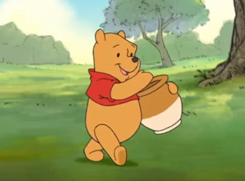 Winnie l'ourson marchant joyeusement avec un pot de miel à la main dans une clairière ensoleillée et herbeuse.