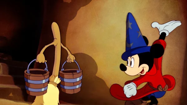 Mickey Mouse, habillé en apprenti sorcier, regarde un balai porter des seaux d'eau dans une scène du film d'animation Disney "Fantasia".