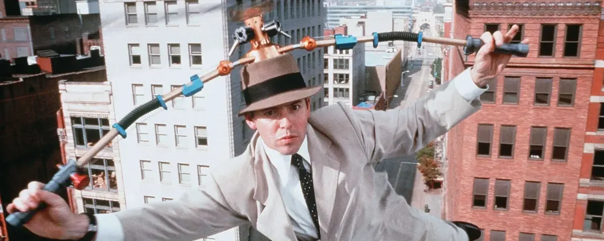 Un homme portant un fedora exécute un numéro d'équilibriste sur un fil électrique entre les bâtiments, utilisant un engin à plusieurs poignées pour maintenir l'équilibre lors de l'événement "Le Noël de Mickey".