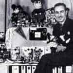 Une photo en noir et blanc d'un homme entouré d'une grande collection de jouets Mickey Mouse et d'articles Walt Disney, affichant divers objets avec un sourire fier.