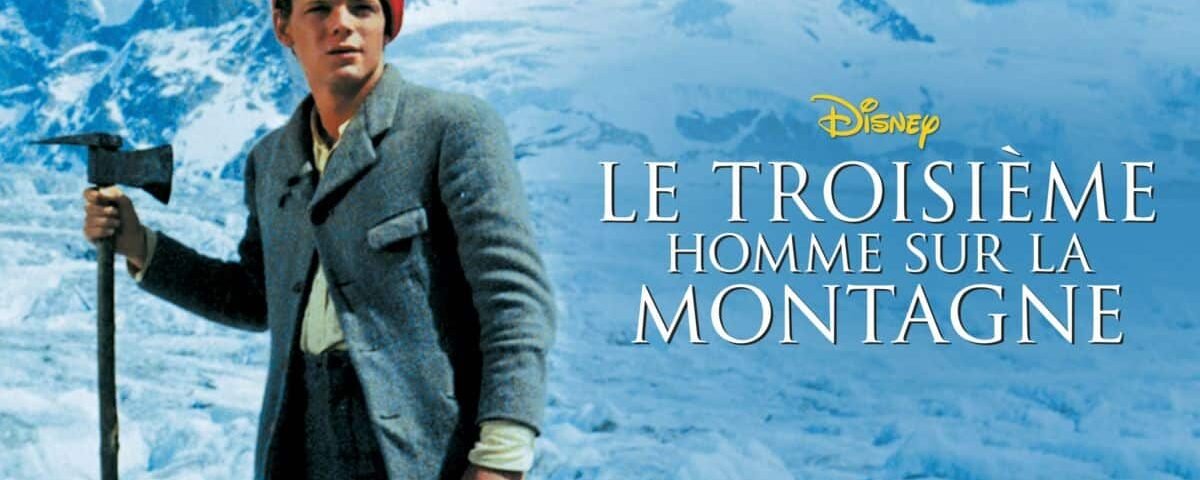 Un homme au bonnet rouge et en tenue d'alpinisme traditionnelle tenant une pioche se tient devant un fond de montagne enneigée, avec le texte « le troisième homme sur la montagne » superposé.
