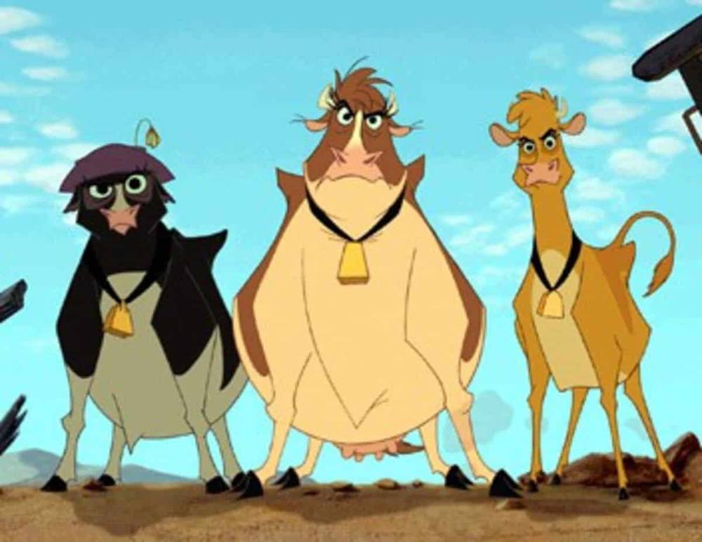 Trois vaches animées du film "La Ferme se Rebelle" debout dans un paysage désertique ; un noir, un marron et un beige, tous portant des cloches.