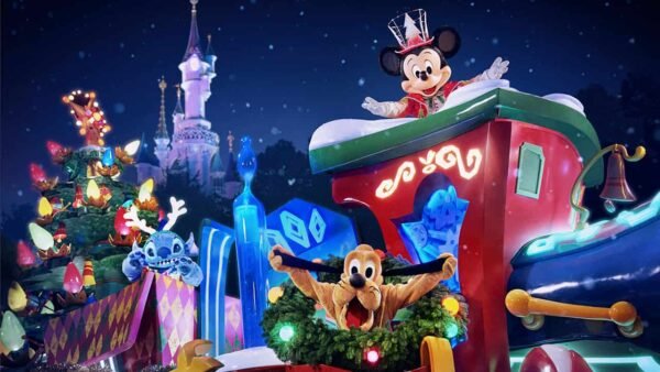Mickey Mouse et Pluton dans un char de Noël festif décoré de lumières, de cadeaux et de guirlandes, avec un château Disneyland éclairé de manière fantaisiste en arrière-plan la nuit.