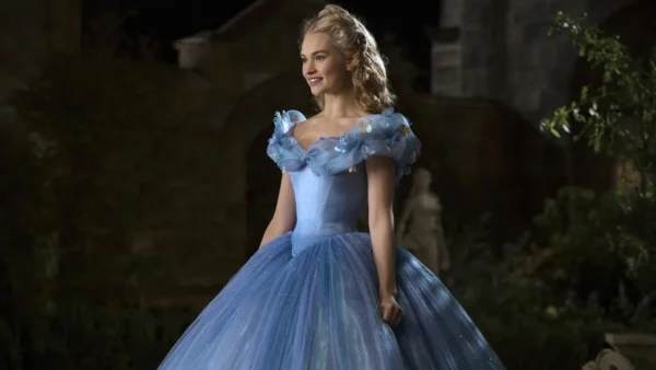 Une femme habillée en Cendrillon se tient dans une grande cour. Elle porte une élégante robe bleue avec de délicats accents floraux et ses cheveux sont coiffés d'un chignon orné. Le décor est la nuit,