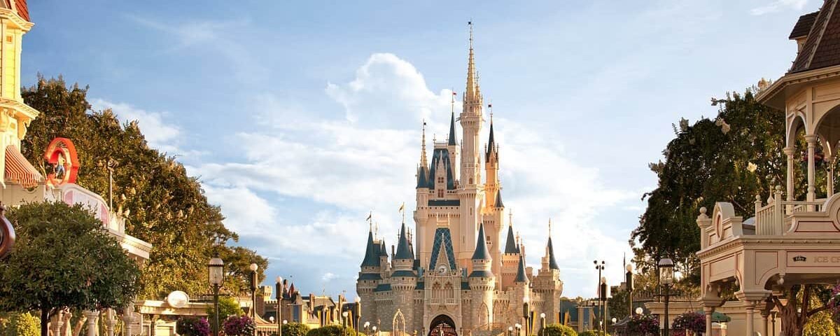 Une vue ensoleillée sur la rue principale du Magic Kingdom, aux États-Unis, menant au château de Cendrillon à Walt Disney World, avec un ciel bleu clair et sans foule.