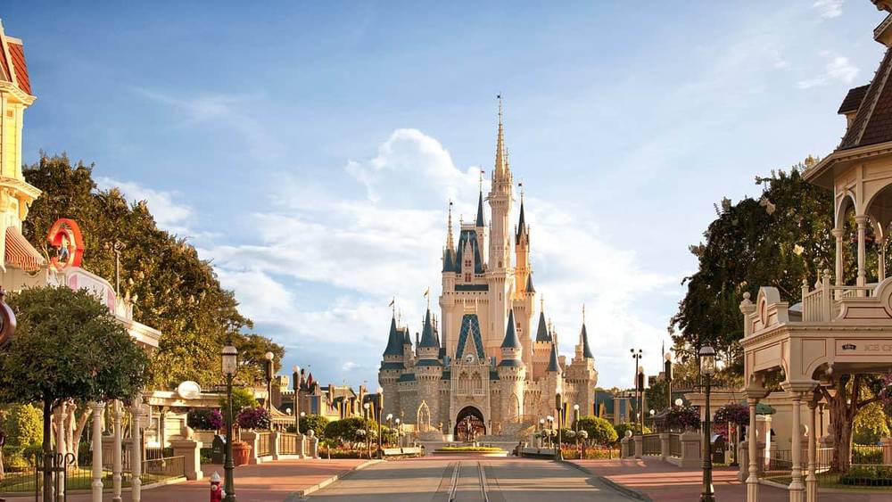 Une vue ensoleillée sur la rue principale du Magic Kingdom, aux États-Unis, menant au château de Cendrillon à Walt Disney World, avec un ciel bleu clair et sans foule.