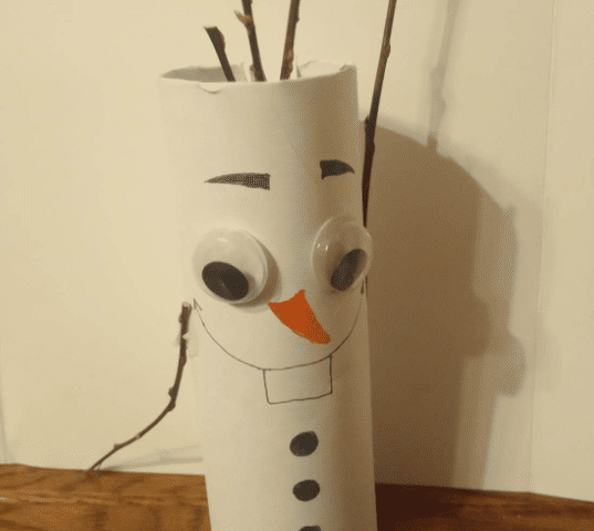 Un Olaf fait main fabriqué à partir d'un rouleau de papier toilette, avec des bras en brindilles, des yeux écarquillés, un nez de carotte en papier et des traits du visage et des boutons dessinés.