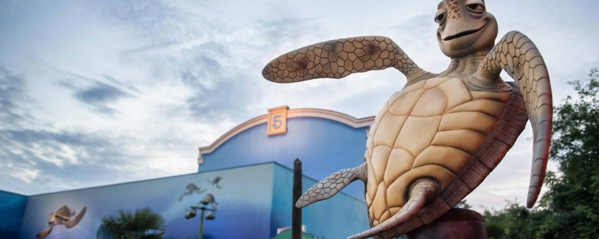 Une statue de Crush, la tortue du Monde de Nemo, devant les studios Walt Disney, avec des peintures murales aux couleurs vives représentant des scènes sous-marines, sous un ciel clair du soir.