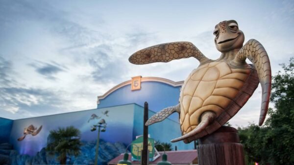 Une statue de Crush, la tortue du Monde de Nemo, devant les studios Walt Disney, avec des peintures murales aux couleurs vives représentant des scènes sous-marines, sous un ciel clair du soir.