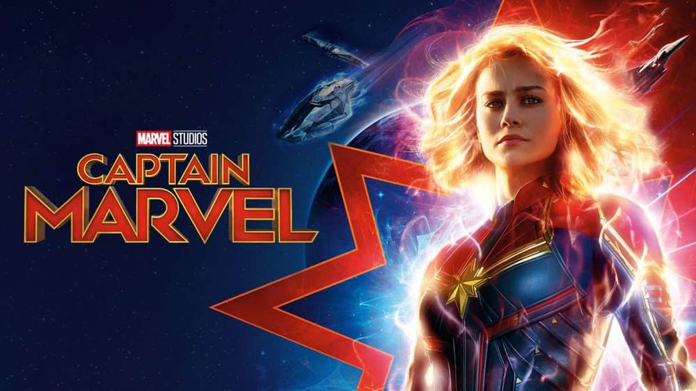 Image promotionnelle pour Captain Marvel de Marvel Studios, mettant en vedette Brie Larson dans une pose puissante avec des effets d'énergie cosmique, sur un fond spatial avec un logo en forme d'étoile.
