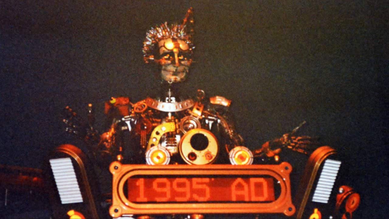Un robot futuriste avec des détails complexes et des éléments lumineux, étiqueté "The Timekeeper 1995 ad", dans un décor faiblement éclairé.