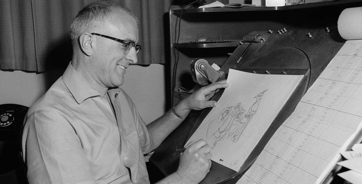 Un homme souriant portant des lunettes dessinant sur une table à dessin, tenant un crayon et regardant le croquis d'un personnage animé de Milt Kahl.