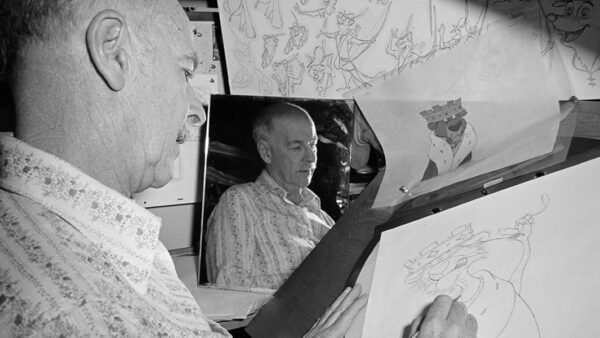 Un homme dessine un personnage de dessin animé sur un bureau à dessin, entouré d’autres illustrations. L'accent est mis sur son dessin à la main et le reflet de son visage dans un miroir, évoquant le style d'Oll.
