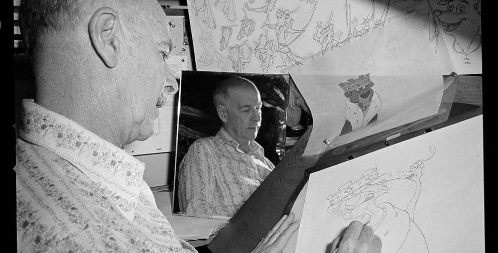 Un homme dessine un personnage de dessin animé sur un bureau à dessin, entouré d’autres illustrations. L'accent est mis sur son dessin à la main et le reflet de son visage dans un miroir, évoquant le style d'Oll.
