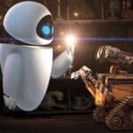 Eve et Wall E, deux robots du « Wall-E » de Pixar, dans une pièce faiblement éclairée remplie d'étagères remplies d'objets. Eve tient une ampoule allumée en direction du Wall E, qui regarde