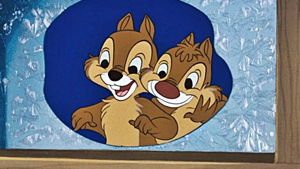 Image de dessin animé de Tic et Tac, deux tamias joyeux, s'embrassant avec de grands sourires, sur un fond ovale bleu avec un effet de verre dépoli.