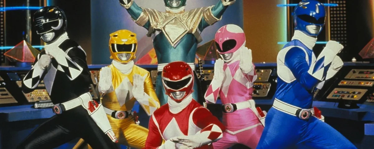 Cinq Power Rangers, vêtus de costumes éclatants (noir, vert, rose, rouge et bleu), prennent une pose triomphale ensemble dans un centre de commandement high-tech.