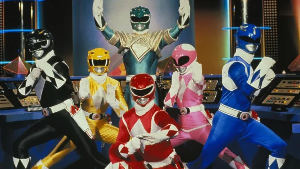 Cinq Power Rangers, vêtus de costumes éclatants (noir, vert, rose, rouge et bleu), prennent une pose triomphale ensemble dans un centre de commandement high-tech.