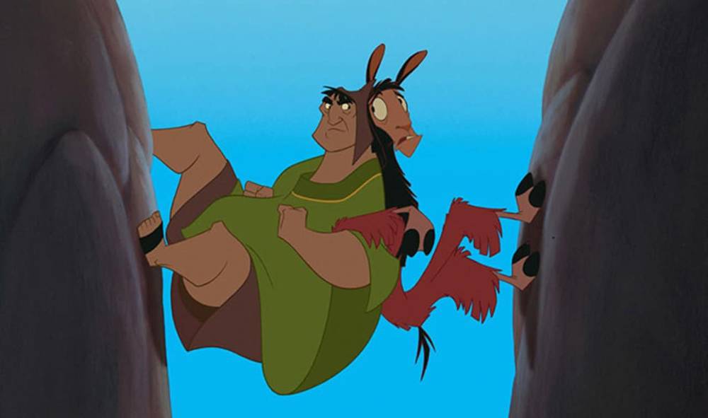 Deux personnages animés, Kuzco et un lama maigre, sont comiquement coincés entre deux imposants murs de falaise, avec des expressions de surprise et d'inconfort.