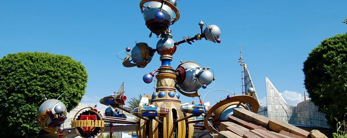 Une sculpture imaginative et futuriste ressemblant à l'Astro Orbiter dans un parc à thème, avec des couleurs vives, des éléments sphériques et des détails mécaniques sous un ciel bleu clair.
