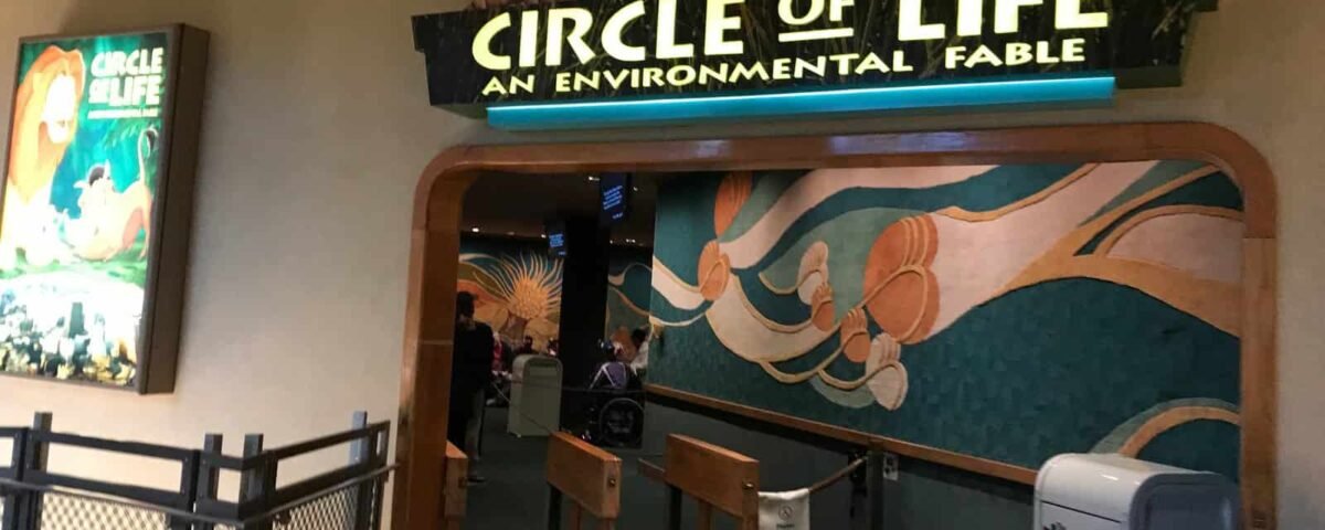Entrée de l'attraction « Cercle de la vie : une fable environnementale », comprenant une enseigne lumineuse avec des personnages de films et une fresque murale représentant les vagues de l'océan à côté d'un portail ouvert.