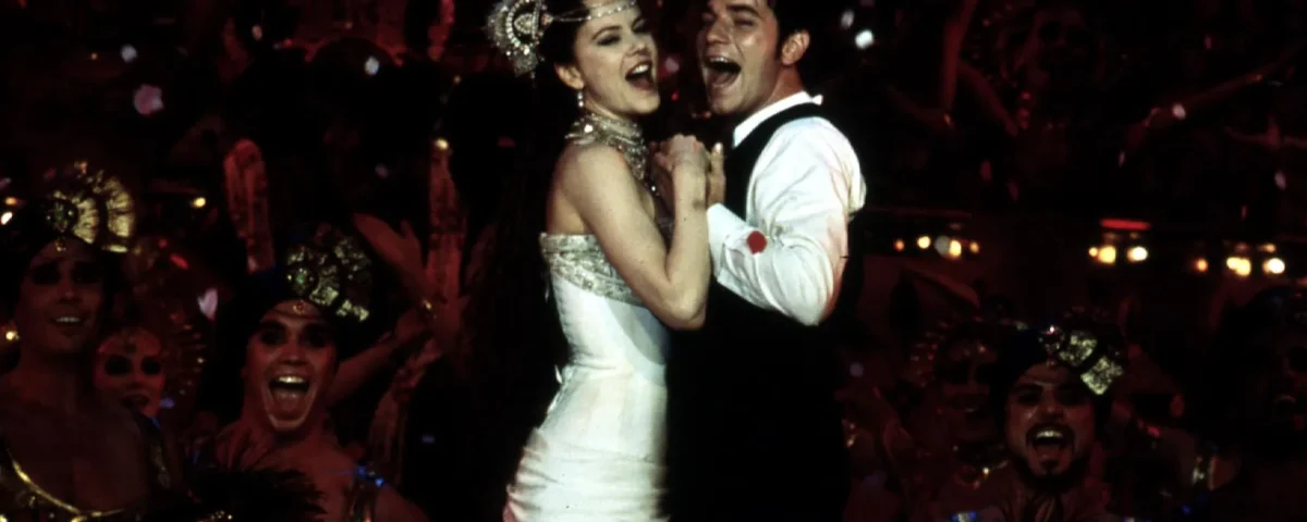 Une scène joyeuse mettant en scène une femme en robe blanche et un homme en smoking dansant en étroite collaboration parmi un groupe d'artistes excités aux costumes vibrants au Moulin Rouge.