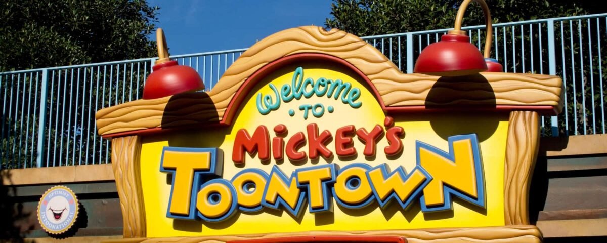 Un panneau vibrant à l'entrée de Mickey's Toontown à Walt Disney World avec des polices audacieuses et fantaisistes, avec des lampes rouges décoratives en haut et un compteur de population en bas.