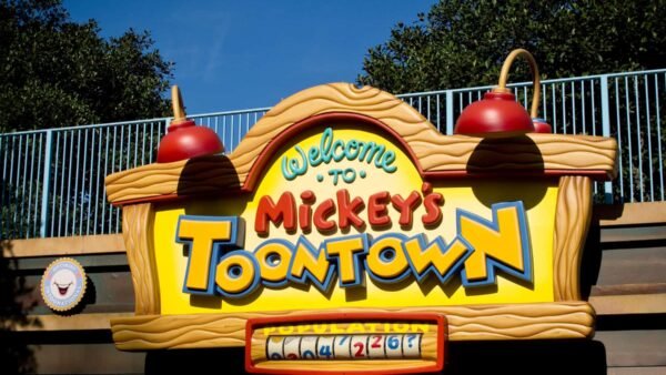 Un panneau vibrant à l'entrée de Mickey's Toontown à Walt Disney World avec des polices audacieuses et fantaisistes, avec des lampes rouges décoratives en haut et un compteur de population en bas.