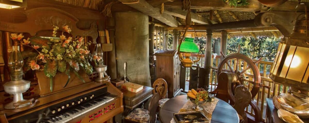 Chambre confortable et rustique avec un éclairage chaleureux, comprenant une table à manger pour deux, un piano vintage, des poutres en bois et une abondance de plantes vertes dans un style cabane familiale suisse