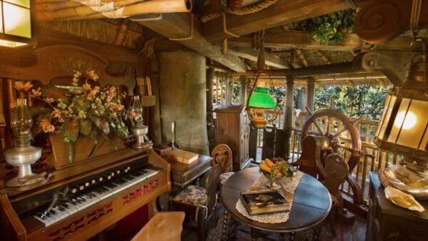 Chambre confortable et rustique avec un éclairage chaleureux, comprenant une table à manger pour deux, un piano vintage, des poutres en bois et une abondance de plantes vertes dans un style cabane familiale suisse