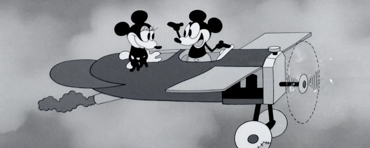 Image animée en noir et blanc de "Plane Crazy" mettant en vedette Mickey et Minnie Mouse dans un avion, se souriant, avec l'hélice qui tourne et des nuages en arrière-plan.