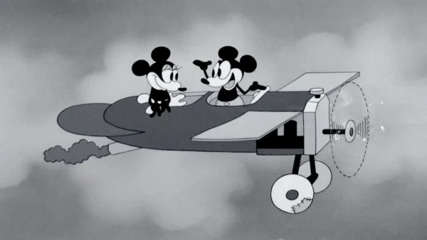 Image animée en noir et blanc de "Plane Crazy" mettant en vedette Mickey et Minnie Mouse dans un avion, se souriant, avec l'hélice qui tourne et des nuages en arrière-plan.