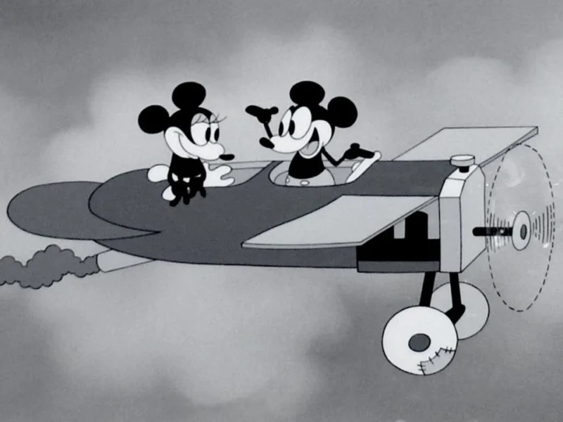 Image animée en noir et blanc de "Plane Crazy" mettant en vedette Mickey et Minnie Mouse dans un avion, se souriant, avec l'hélice qui tourne et des nuages en arrière-plan.