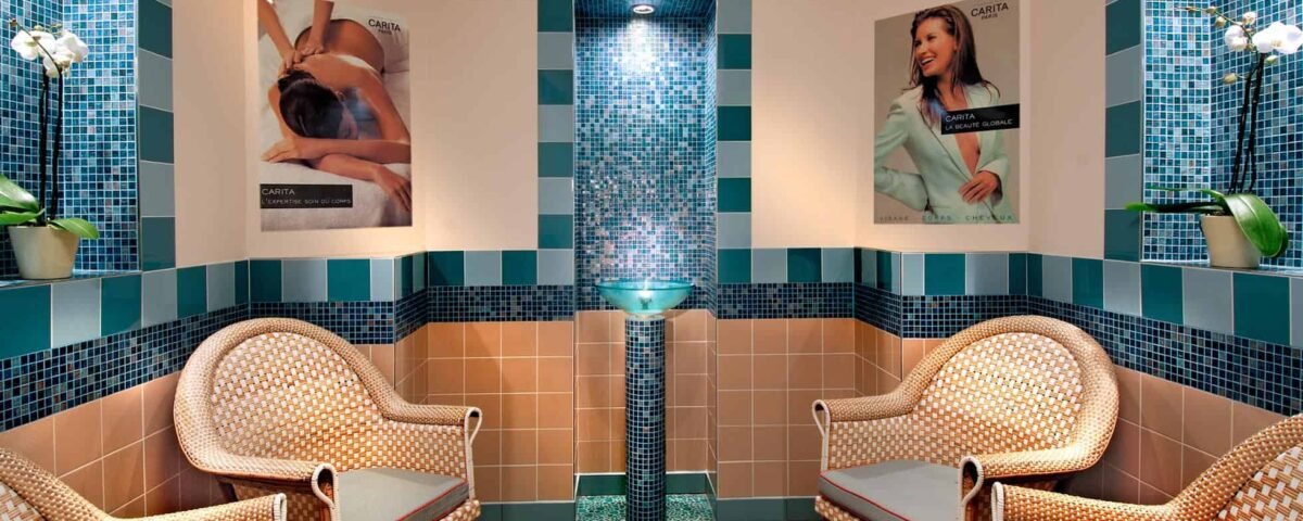 Une salle de relaxation spa à l'hôtel Disneyland avec deux chaises en osier faisant face à une pièce d'eau centrale en mosaïque, entourée de murs carrelés et ornée d'affiches de soins spa.