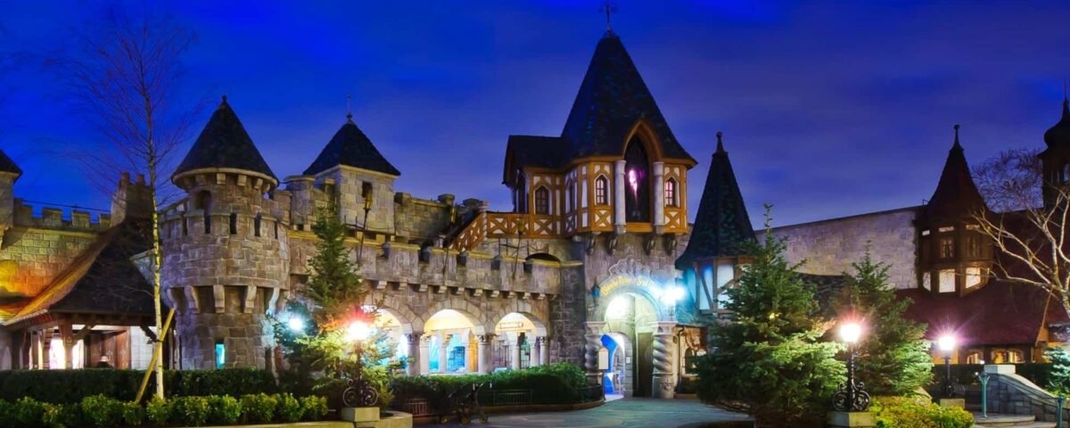Crépuscule sur un château sur le thème du pays fantastique avec des lampadaires illuminés.
