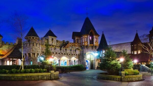 Crépuscule sur un château sur le thème du pays fantastique avec des lampadaires illuminés.
