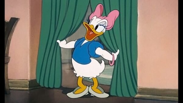 Image animée de Daisy Duck souriant et posant avec assurance, debout devant un rideau vert avec un chemisier bleu et un nœud rose sur la tête.