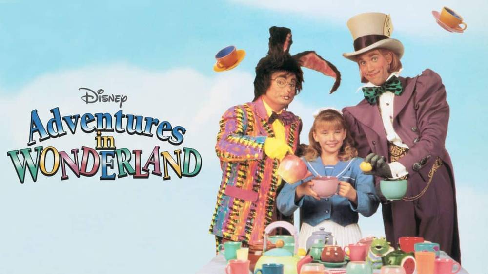 Image promotionnelle pour "Aventures au pays des merveilles" mettant en vedette trois personnages vêtus de costumes colorés, debout parmi un ensemble flottant de tasses à thé et de soucoupes, avec un titre au style fantaisiste.
