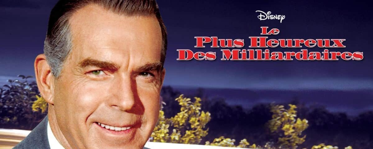 Image promotionnelle pour un film de Disney intitulé "Le Plus Heureux des Milliardaires", mettant en vedette un homme caucasien souriant d'âge moyen vêtu d'un costume, sur fond de ciel crépusculaire.