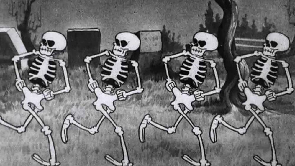 Caricature en noir et blanc des Silly Symphonies montrant cinq squelettes dansant joyeusement dans un cimetière.