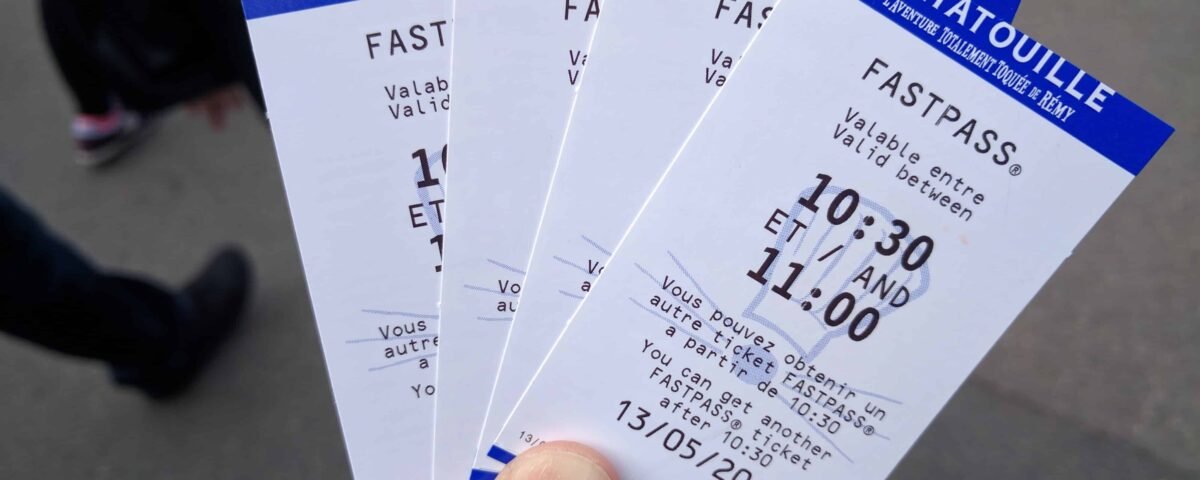 Une main tenant trois billets fastpass pour l'attraction Indiana Jones et le Temple du Péril à l'Envers dans un parc à thème, indiquant une fenêtre horaire de retour de 10h30 à
