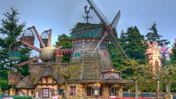 Une scène de parc d'attractions fantaisiste mettant en vedette des pirouettes du vieux moulin avec des outils de jardin ludiques et surdimensionnés et des fleurs colorées, sous un ciel nuageux.